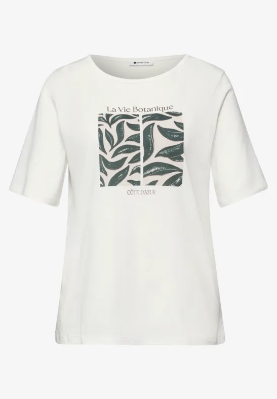 Weißes T-Shirt mit kurzem Arm, mittig ein grünes Blattmuster und Text 'La Vie Intemporelle' und 'Christine'.