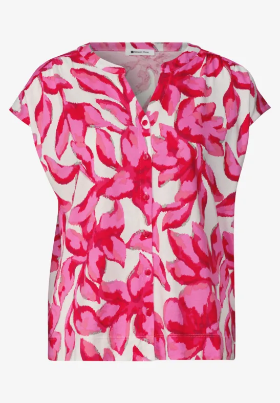 Blouse courte femme à motif floral rose vif sur fond blanc, col rond et coupe ample.