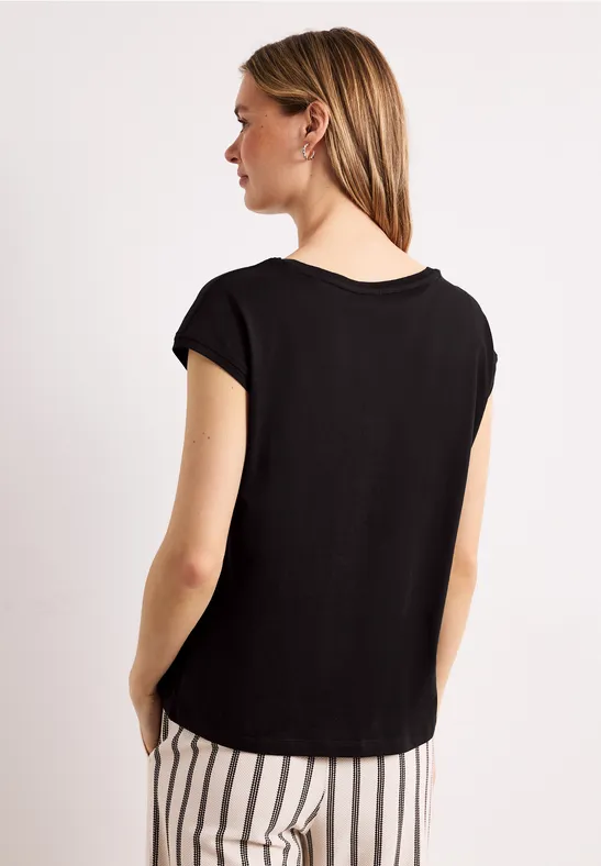 Vrouw van achteren in zwart shirt en zwart-witte gestreepte broek