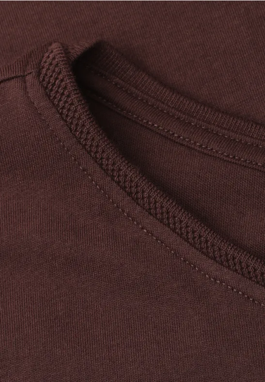 Close-up van de ronde hals van een bruin t-shirt met zichtbare stiksels