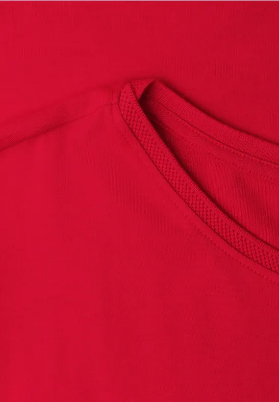Close-up van een rood T-shirt met zichtbare halslijn en naden.