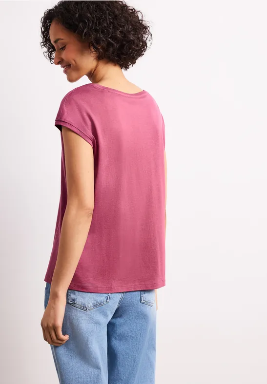 Frau von hinten mit pinkem T-Shirt und hellblauen Jeans.