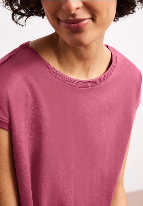 Frauenoberkörper in einem ärmellosen rosafarbenen Shirt