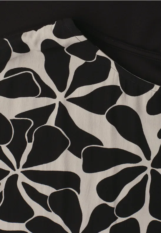 Close-up van een kledingstuk met een zwart-wit abstract bloempatroon.