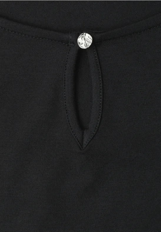Schwarzes Shirt mit kleinem Tropfenausschnitt und funkelndem Kristallknopf.