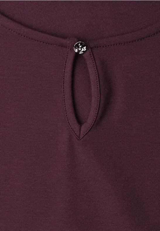 Bordeauxkleurig shirt met kleine druppelvormige halsuitsnijding, gesloten met een ronde sierknop.