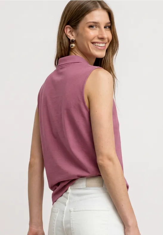 Vrouw gezien van achter, draagt een roze mouwloze top en een witte broek.