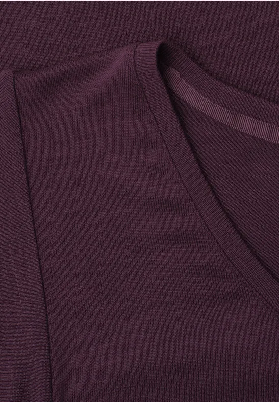 Close-up van een donkerpaars T-shirt met ronde hals en zichtbare schoudernaden.