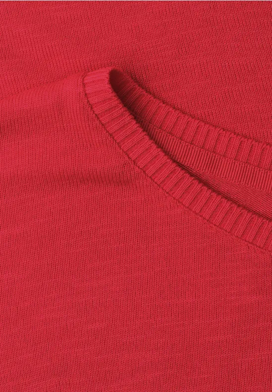 Close-up van een rood gebreid shirt met ronde hals