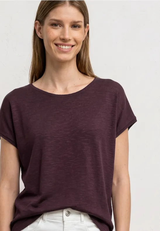 Een vrouw draagt een effen bordeauxrood T-shirt met korte mouwen voor lichte achtergrond.