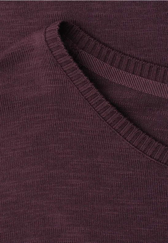 Detailopname van een bordeauxrode top met geribbelde ronde hals.