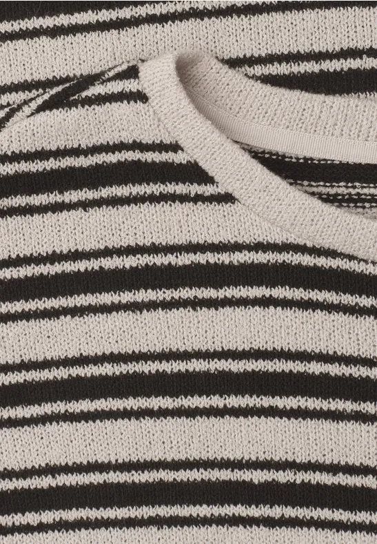 Close-up van gebreide stof met onregelmatige zwarte en witte horizontale strepen.