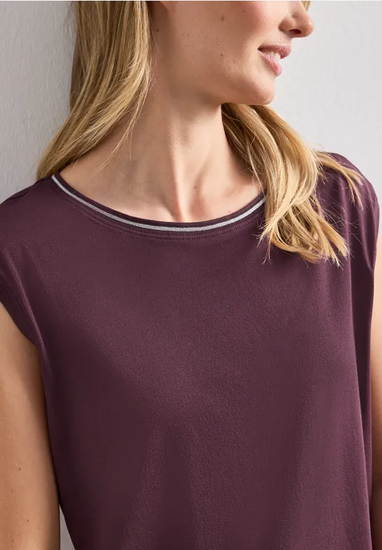 Blonde vrouw in mouwloze, paarse top met lichte kraag