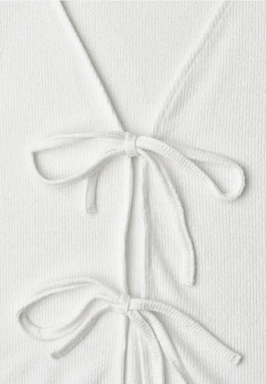 Weißes Strickoberteil mit zwei dekorativen Schleifen