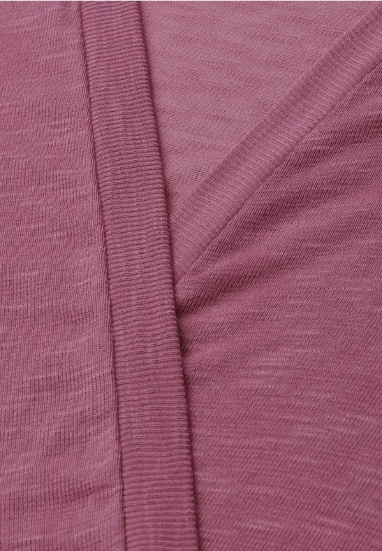 Close-up van een roze stof met fijne structuur en zichtbare naad.