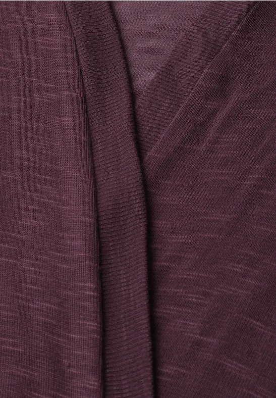 Gros plan sur un cardigan tricoté bordeaux à col en V croisé.