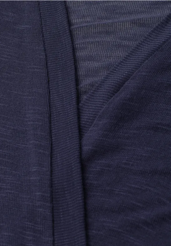 Gros plan sur un tissu bleu marine fin et extensible avec un rabat superposé.
