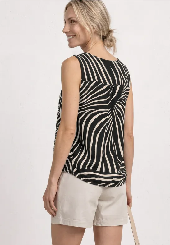 Vrouw van achter in zwart-wit gestreept top met knoop en lichte shorts, tas over de schouder.