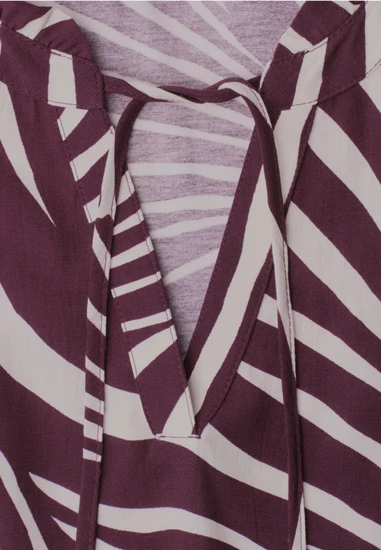 Close-up van een paars-wit gestreept shirt met V-hals en bindkoord.