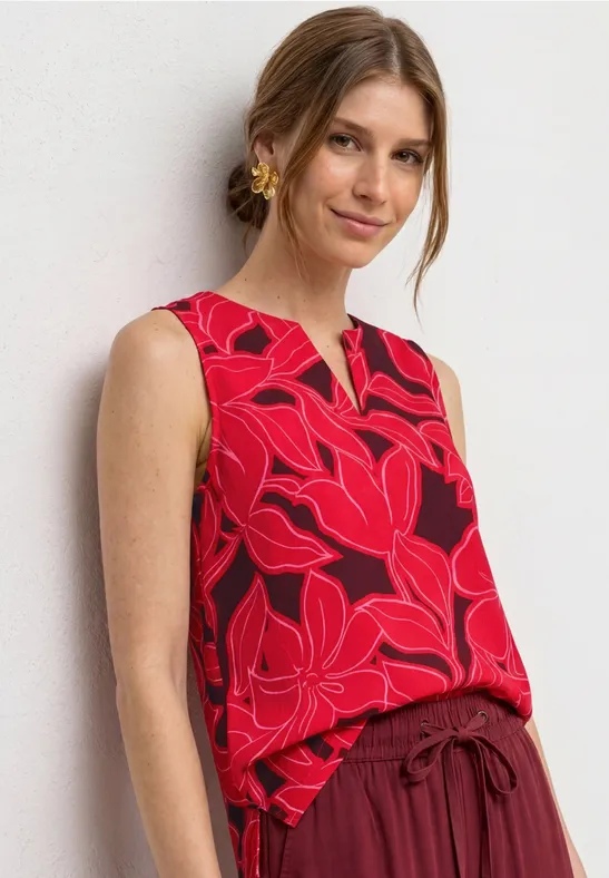 Vrouw met rood mouwloos topje met roze bloemenprint.