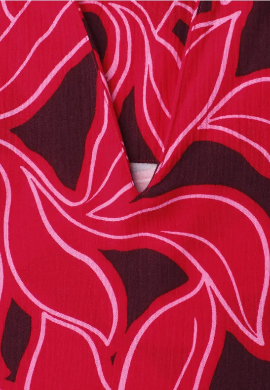 Rood textiel met sierlijke, roze lijnen in een bloemenmotief.