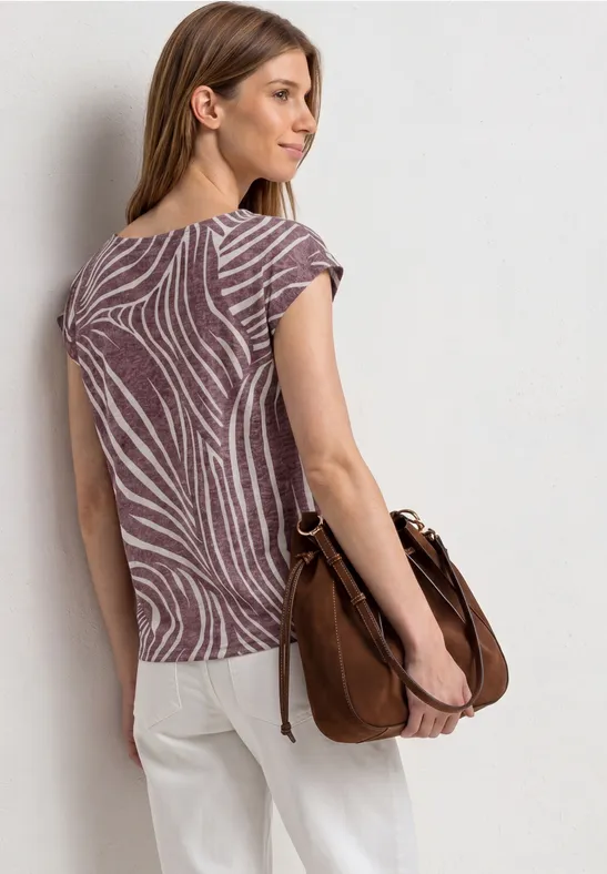 Vrouw van achteren met een gemêleerde blouse en lichte broek, met een bruin schoudertasje.