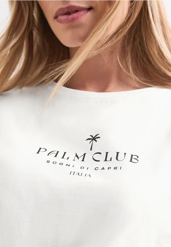 Nahaufnahme eines weißen T-Shirts mit schwarzem „Palm Club Sorrento, Capri Italia“-Schriftzug und Palmen-Icon.