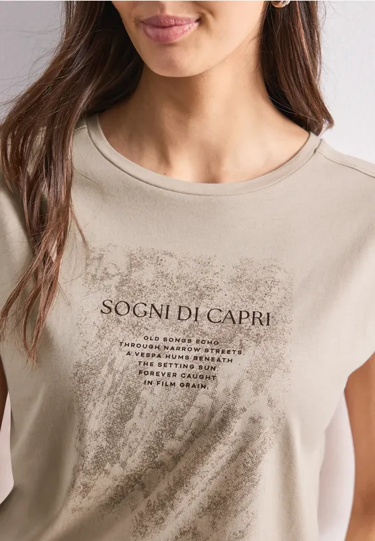 Beige T-shirt gedragen door een vrouw met 'Sogni di Capri'-opdruk en penseelstreekpatroon.