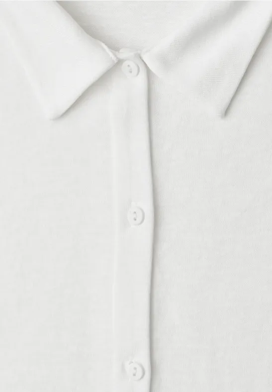 Nahaufnahme eines weißen Poloshirts mit Kragen und drei Knöpfen.