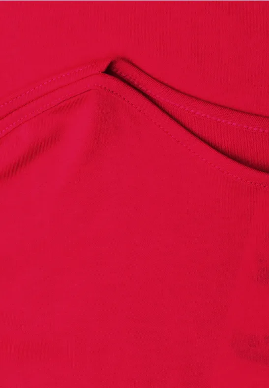 Rood kledingstuk van stof met zichtbare naad en klein zakje.