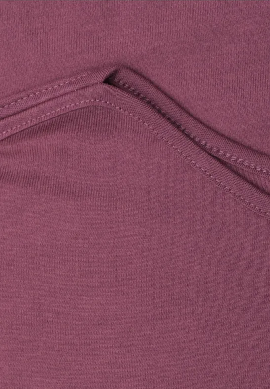 Close-up van paars textiel met stiksel en zakplooi.