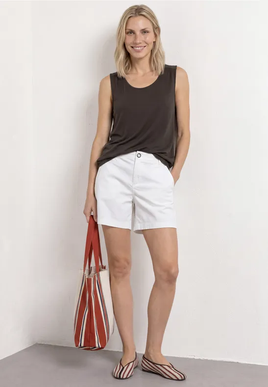 Vrouw in zwart topje, witte shorts, zwart-witte sandalen en grote rood-witte tas.