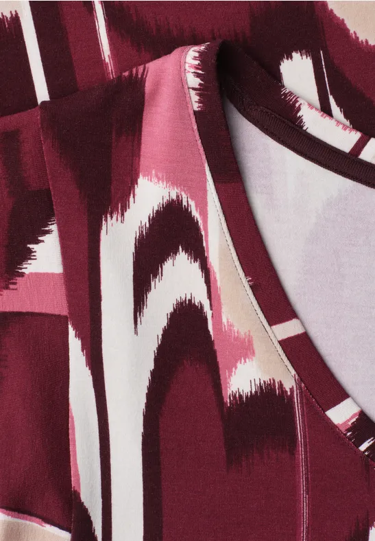 Close-up van een rood-wit abstract patroon op stof, waarschijnlijk kleding.