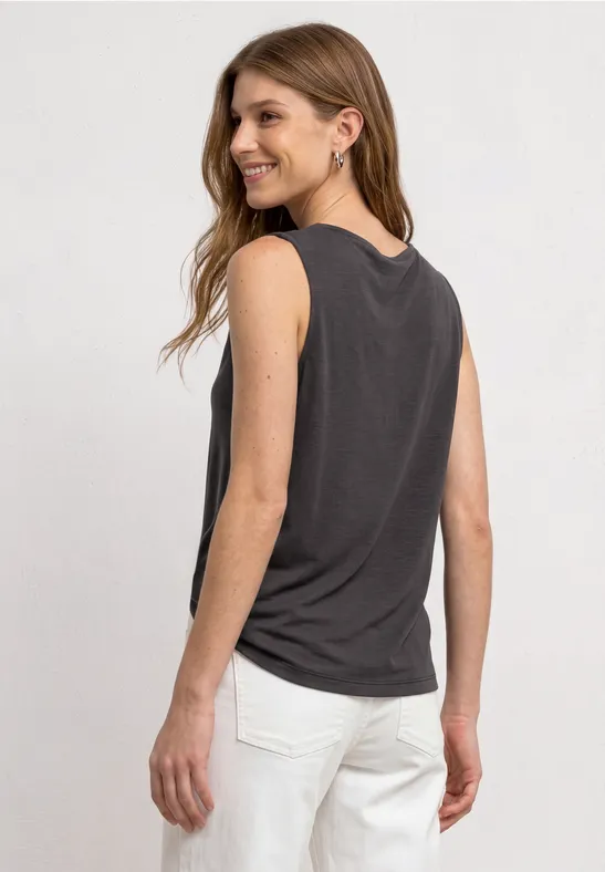 Jonge vrouw gezien van achteren met een zwart mouwloos topje en witte broek.