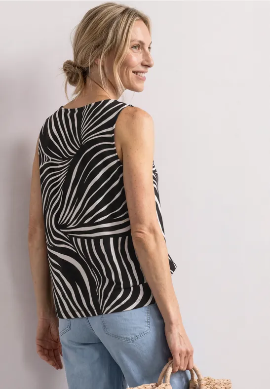 Frau von hinten in Zebra-Muster-Top und Jeans, mit einer Tasche in der Hand.
