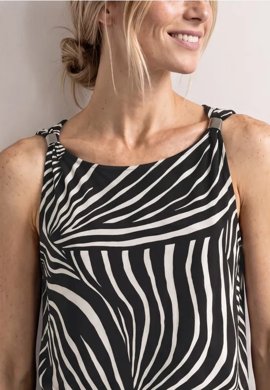 Frau in naher Aufnahme, trägt ein ärmelloses Oberteil mit Zebra-Muster und lächelt.