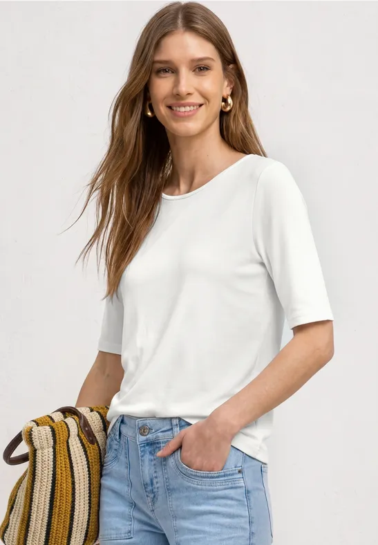 Dame in weißem Halbarmshirt und blauen Jeans mit gestreifter Umhängetasche.