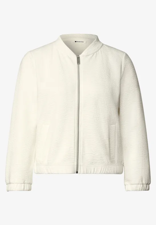 Bomber épuré de couleur crème avec fermeture éclair et poches latérales.