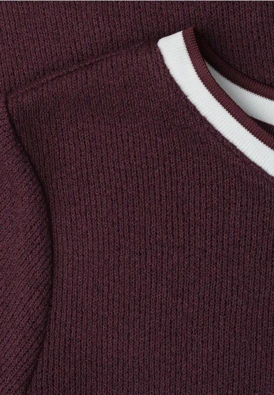 Close-up van een mouwloos bordeaux gebreid top met witte bies rond de ronde hals
