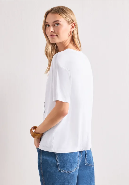Seitliche Ansicht einer Frau mit weißem T-Shirt und blauen Jeans vor hellem Hintergrund.
