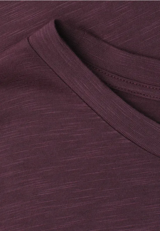 Close-up van een bordeaux T-shirt met ronde hals, met fijne weefstructuur zichtbaar.