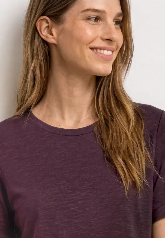 Vrouw in paars T-shirt met lang haar, schouders en nek zichtbaar