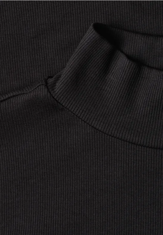 Nahaufnahme eines schwarzen Rollkragenpullovers aus geripptem Stoff.