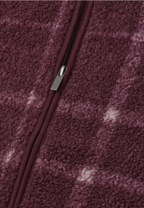 Blick auf einen geschlossenen Reißverschluss an weichem, burgunderfarbenem Fleece mit dezentem Karomuster.