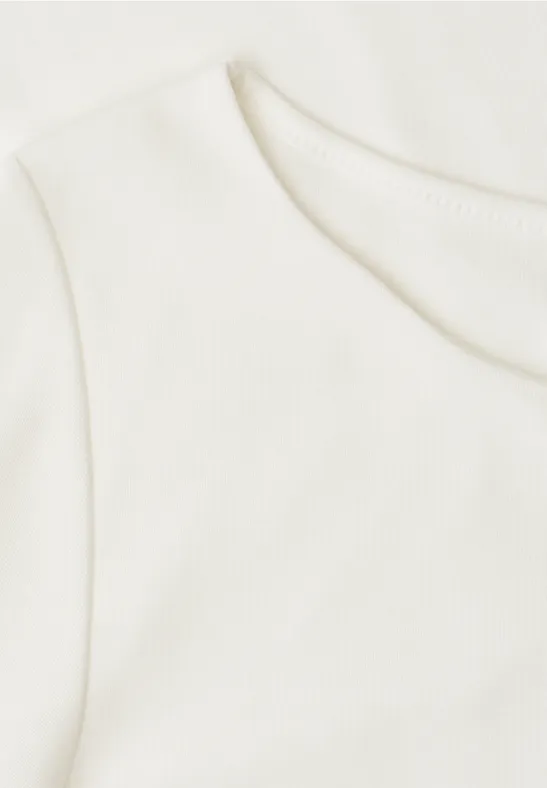 Gros plan d’un T-shirt blanc à encolure ronde sur fond clair.