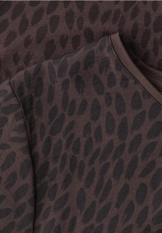 Gros plan d’un vêtement marron orné d’un motif irrégulier de gouttes brun foncé.