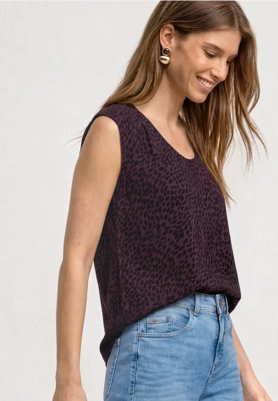 Femme portant un débardeur violet à motifs et un jean bleu clair