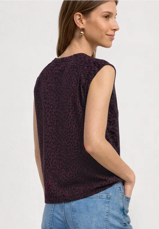 Haut sans manches sombre à motif léopard violet subtil, porté avec un jean bleu clair.