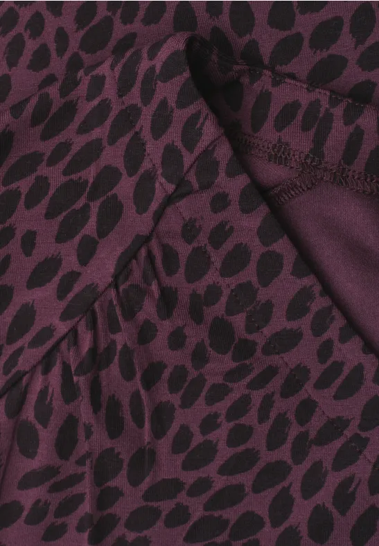 Gros plan d'un tissu violet foncé à motif de feuilles noires