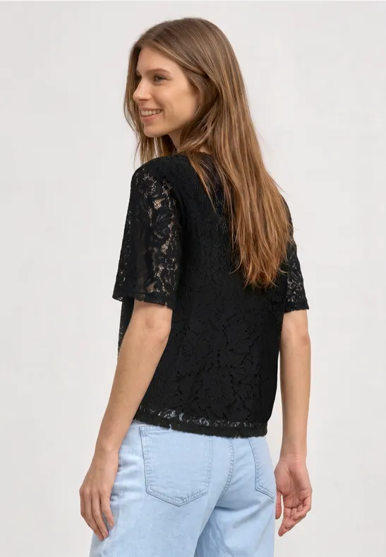 Frau von hinten in schwarzer Spitzenbluse mit kurzen Ärmeln und blauer Jeans.